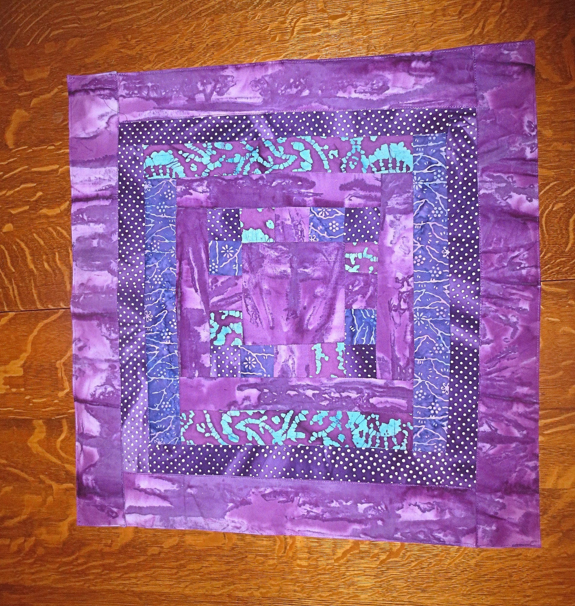 all purples batiks quilted insulated log cabin table runner with a splash of color