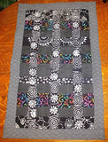 black batik and calico quilted insulated table runner with a splash of color